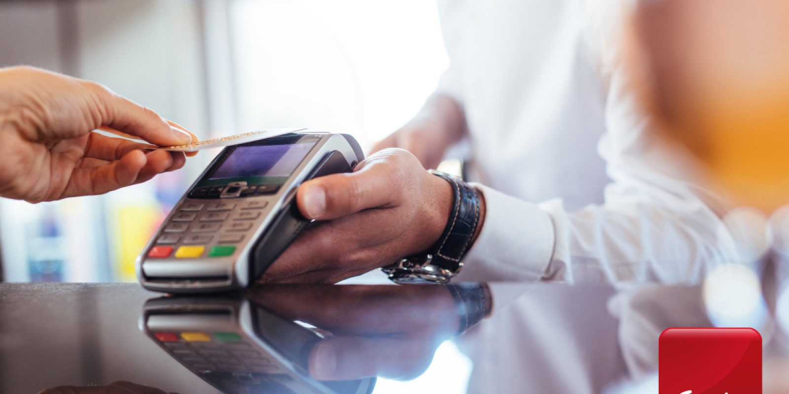 Hand of customer paying with contactless credit card with NFC technology. Bartender with a credit card reader machine at bar counter with female holding credit card. Focus on hands.